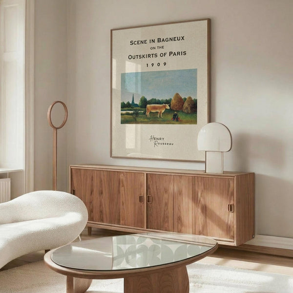 May include: Henri Rousseau vintage art poster displayed above wooden sideboard in minimalist living room. Cream-colored print features pastoral scene with cow, haystacks, and countryside landscape in muted greens and blues. Modern white sculptural chair and glass coffee table complete the Scandinavian-style interior with natural wood tones and soft lighting.