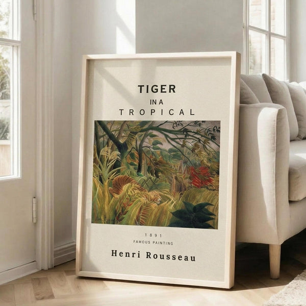 May include: Framed art print displayed in bright living room setting, leaning against white wall next to beige upholstered chair. Print features lush tropical jungle scene with dense green foliage, palm fronds, and orange tiger partially hidden among vegetation. White matted poster with black text above and below central artwork image, housed in natural wood frame. Sunlight streams through tall windows onto hardwood floors.