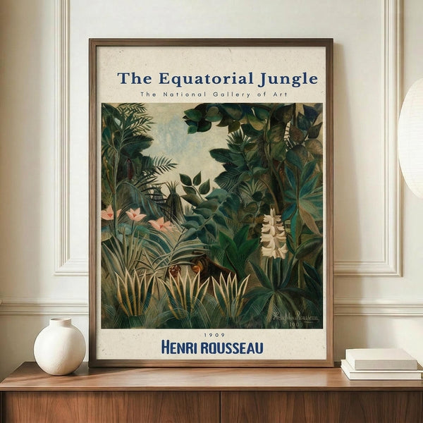 May include: Framed vintage art poster featuring a lush tropical jungle scene with dense green foliage, palm fronds, flowering plants in pink and white, displayed on a wooden console table beside a cream ceramic vase and stacked books against white paneled walls in a bright, minimalist room setting.