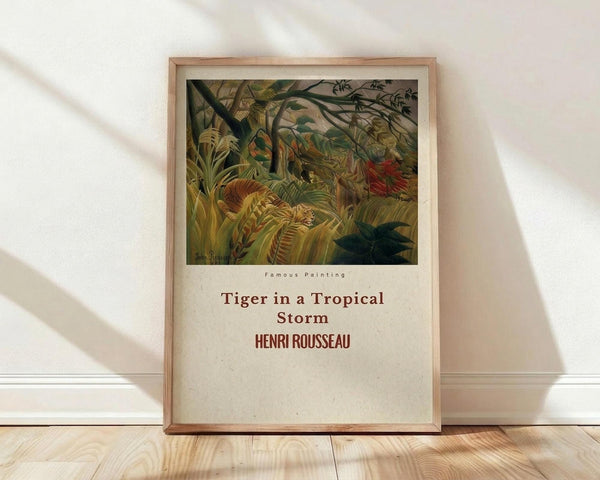 May include: Framed poster print leaning against white wall on light wooden floor with natural sunlight streaming across the scene. The artwork shows a lush jungle scene with dense tropical foliage in greens and yellows, featuring a tiger partially hidden among large palm fronds and exotic plants. Below the colorful botanical illustration is cream-colored text area with the painting title and artist name in brown lettering. The frame appears to be natural light wood tone.