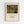 May include: Framed art print hanging on white wall showing Henri Rousseau's jungle painting with a tiger hidden among lush tropical foliage in greens, yellows, and earth tones. Light wood frame with cream matting displays the vintage-style reproduction poster with text below the artwork.