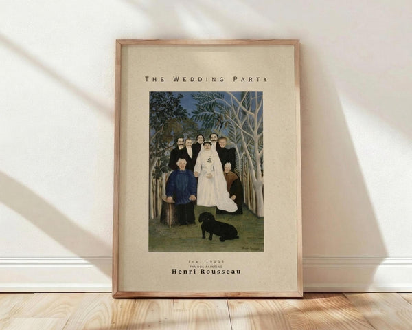 May include: Framed art print of Henri Rousseau's "The Wedding Party" painting from 1905, showing a bride in white dress surrounded by wedding guests in dark formal attire standing among tropical foliage with a small black dog at their feet. The print features cream matting in a light wooden frame, displayed on wooden flooring against a white wall with soft natural lighting creating diagonal shadows.