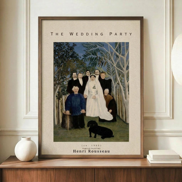 May include: Framed art print of Henri Rousseau's "The Wedding Party" painting displayed on wooden credenza beside white ceramic vase and books. Print shows bride in white dress surrounded by wedding party in dark formal wear, set in lush jungle landscape with tropical plants and small black dog. Cream matting with brown frame against white paneled wall.