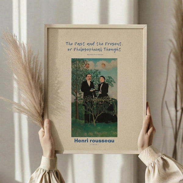 May include: Person in cream ruffled blouse holding framed art print and dried pampas grass against white curtained window. The vintage-style poster features a surreal painting with two figures in dark clothing seated beneath a tree, with floating faces in the sky above. Warm beige matting surrounds the colorful artwork in a light wood frame.