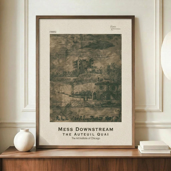 May include: Framed art print featuring Henri Rousseau's 1885 etching of riverside buildings and castle ruins in muted green and beige tones, displayed on wooden sideboard next to white ceramic vase and stacked books against cream wainscoted wall