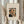 May include: Hands holding a framed art print featuring Henri Rousseau's self-portrait showing a balding man with mustache in dark formal wear beside an oil lamp, displayed against white curtains with dried wheat stalks visible on the left side