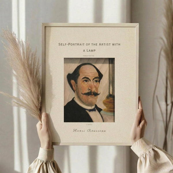 May include: Hands holding a framed art print featuring Henri Rousseau's self-portrait showing a balding man with mustache in dark formal wear beside an oil lamp, displayed against white curtains with dried wheat stalks visible on the left side