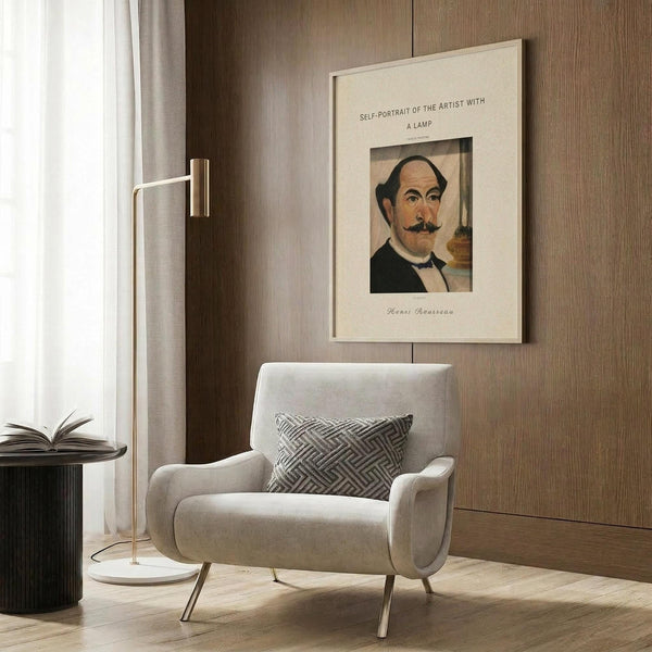 May include: Vintage art poster featuring Henri Rousseau's self-portrait displayed in modern living room with beige armchair, geometric patterned pillow, brass floor lamp, and dark wood wall paneling. The framed print shows a mustachioed man in dark clothing against cream matting with vintage typography above and signature below.
