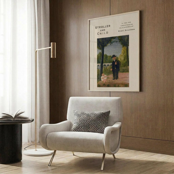 May include: Henri Rousseau vintage art print displayed in modern living room with beige armchair, geometric pillow, brass floor lamp, and dark wood paneling. The framed poster shows a man in dark clothing standing near a small child in a park setting with trees and bridge in background. Warm neutral tones throughout the staged interior scene.