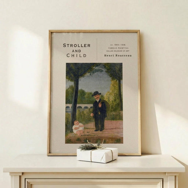 May include: Framed art print featuring Henri Rousseau's naive style painting of an elderly man in dark suit and hat standing beside a small child in white dress on a tree-lined path. The poster has cream matting with black text reading "Stroller and Child" and artist information. Natural wood frame sits on light wooden surface next to small white wrapped gift with twine and greenery sprig against neutral beige wall.