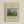 May include: Framed art print displaying Henri Rousseau's 1910 pastoral painting featuring cows grazing in a green meadow with tall poplar trees and a large rounded tree under a pale blue sky. The cream-colored poster includes the title "Meadowland (The Pasture)" and artist name in elegant typography. Natural wood frame hangs on a light beige wall.