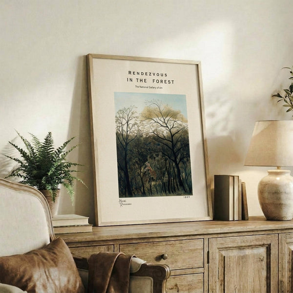 May include: Framed art print featuring a lush forest scene with tall trees and foliage in green and blue tones, displayed on a rustic wooden sideboard alongside books, a fern plant, ceramic vase, and table lamp in a cozy living room setting with neutral walls and upholstered furniture.