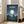 May include: Framed poster displaying a moonlit night scene with two silhouetted children standing beside a large creature on a hill, featuring Japanese text at top and English subtitle below. Dark blue starry sky with bright full moon illuminates rolling countryside landscape. Light wood frame leans against white wall beside beige upholstered chair in bright room with large windows.