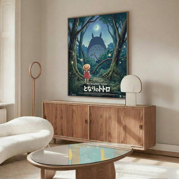 May include: Studio Ghibli-inspired poster showing a small child in red dress standing in moonlit forest facing large silhouetted creature among trees. Artwork features deep blue night sky with crescent moon, lush green foliage, and Japanese text. Displayed above mid-century modern walnut credenza in minimalist living room with cream walls, white curved chair, and glass coffee table.