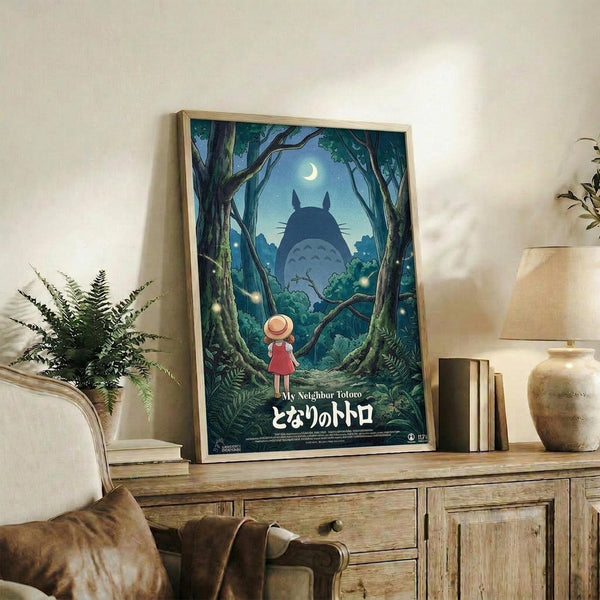 May include: Framed poster featuring animated forest scene with small girl in red dress and hat looking up at large silhouetted creature among trees under crescent moon, displayed on rustic wooden console with books, potted fern, and ceramic vase in cozy living room setting with beige armchair