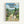 Framed poster featuring the iconic Studio Ghibli characters Totoro in a peaceful Japanese countryside village scene. The artwork shows a large gray Totoro with smaller blue Totoro and white spirit, alongside two children on a dirt path surrounded by traditional wooden houses, lush green trees, rolling hills, and power lines under a cloudy blue sky. The poster has Japanese text at the top with "My Neighbor Totoro" in English below, displayed in a light wooden frame against a white background.