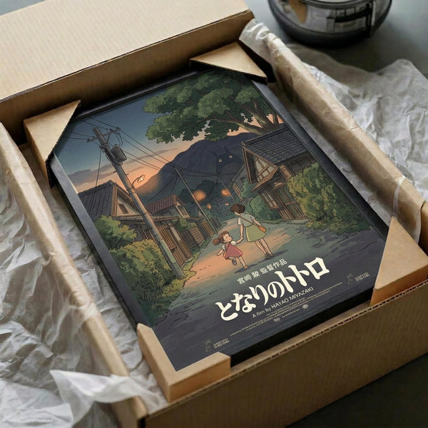 May include: Framed poster artwork showing an illustrated evening scene with two children walking past traditional Japanese houses, power lines, and lush green trees under a dusky sky. The print is carefully packaged in a brown cardboard box with protective white tissue paper, displaying the poster's rich colors and detailed animation-style artwork against a neutral surface.