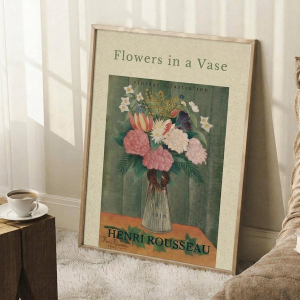 May include: A framed vintage botanical poster leaning against white walls on a textured cream rug. The artwork shows colorful flowers including pink peonies, white daisies, and red tulips in a ribbed glass vase against a teal green background with an orange banner below. A white coffee cup sits on a wooden block nearby, with soft natural lighting creating shadows on the wall.