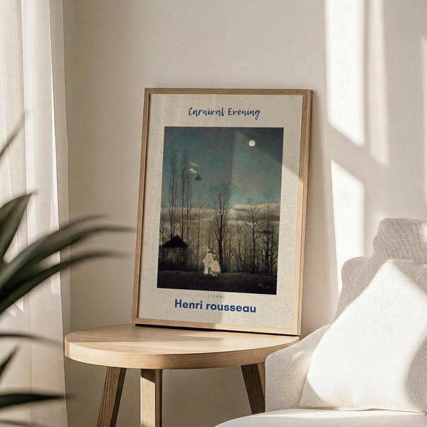 May include: Framed art print displaying a twilight forest scene with bare trees, full moon, and small figures near a cottage. The vintage-style artwork features muted blues and greens in a thin wooden frame with cream matting. Print sits on a round wooden side table next to a beige upholstered chair with decorative pillow, beside a potted plant with long leaves casting shadows on white walls in bright natural lighting.