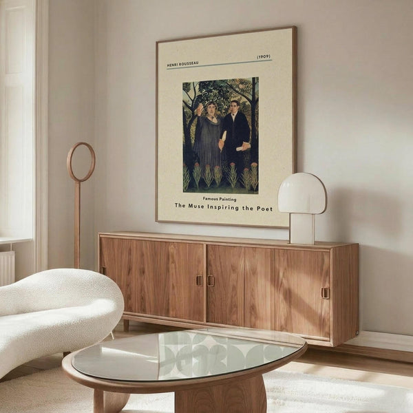 May include: Henri Rousseau art print showing two figures in dark clothing standing among lush green jungle foliage, displayed in thin brown frame on cream wall above wooden sideboard. Modern living room setting with white curved chair, glass oval coffee table, and minimalist table lamp. Warm natural lighting creates shadows on polished surfaces.