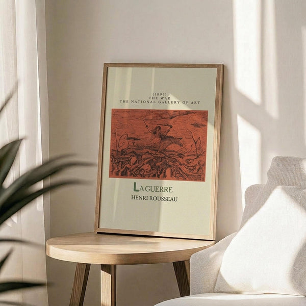 May include: Framed vintage art print displayed on light wood round side table next to beige upholstered chair. Print shows reddish-orange illustration with dark figures in dramatic scene, cream colored matting, and thin wood frame. Natural lighting creates soft shadows on white wall behind, with green plant leaves visible in corner.