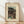 May include: Framed vintage Japanese woodblock print showing evening scene with figures walking near water under large tree, pagoda in background, muted earth tones with blue accents, cream matting in light wood frame, leaning against white wall on wooden floor with natural sunlight shadows