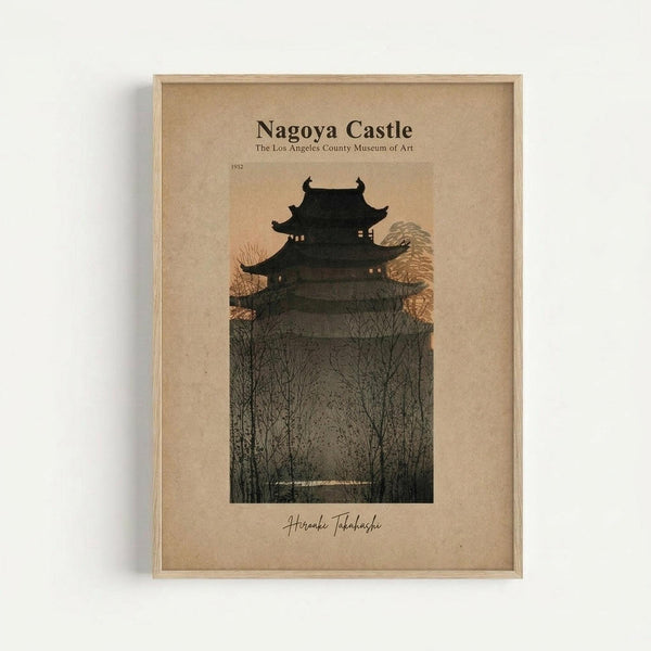 Framed vintage-style art print featuring a Japanese castle silhouetted against a twilight sky. The multi-tiered pagoda structure sits atop a hill surrounded by bare winter trees, rendered in dark tones with warm peachy-orange sky behind. Text reads "Nagoya Castle" and "The Los Angeles County Museum of Art" with "1932" and artist signature below. Natural wood frame with beige matting, mounted on white wall.