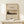 May include: Framed vintage-style poster featuring Mount Fuji landscape with trees in foreground, displayed on light wood shelf against cream wall. Natural wood frame surrounds beige poster with Japanese mountain scene in muted earth tones. Small white wrapped gift with twine and pine sprig sits beside frame.