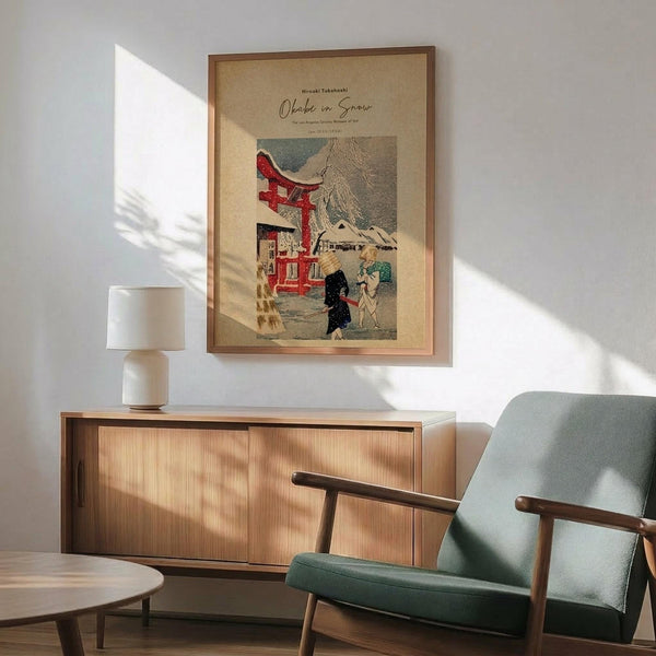 May include: Japanese woodblock print poster in wooden frame hanging above modern credenza, showing snowy winter scene with red torii gate, traditional buildings, and figures with umbrellas. Mid-century mint green armchair with wooden arms positioned nearby, white table lamp on sideboard, natural sunlight casting shadows across white wall in contemporary living room setting.