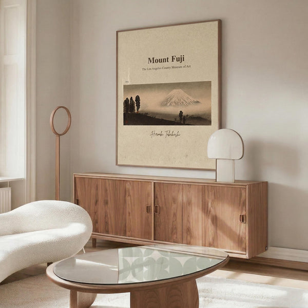 a living room with a large framed poster of Mount Fuji hanging on the wall, a wooden cabinet, a white sofa, and a glass coffee table.