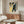 May include: Framed Japanese woodblock print featuring white cherry blossoms against yellow and blue background, displayed above walnut credenza in modern living room with white curved chair, glass oval coffee table, and neutral walls