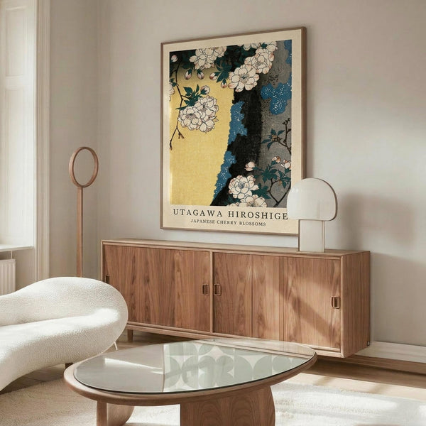 May include: Framed Japanese woodblock print featuring white cherry blossoms against yellow and blue background, displayed above walnut credenza in modern living room with white curved chair, glass oval coffee table, and neutral walls