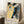 May include: A framed poster featuring Japanese cherry blossoms with white flowers on dark branches against a yellow and blue background with decorative dots, displayed in a light wood frame leaning against white walls in a cozy room setting with a coffee cup on a wooden side table and beige textured throw blanket nearby.