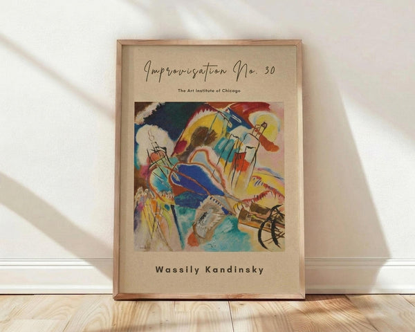 May include: Framed Wassily Kandinsky abstract art print featuring vibrant swirling forms in blues, yellows, reds, and greens with geometric and organic shapes. Museum poster style with cream background and simple text layout. Natural wood frame leaning against white wall on light wooden floor with soft shadows from window light.