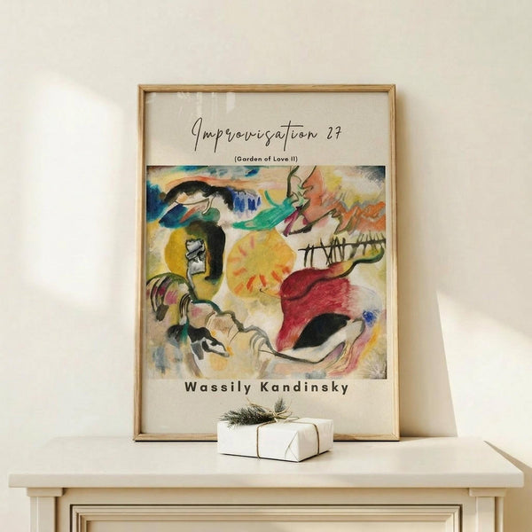 May include: Abstract expressionist artwork poster in wooden frame displayed on light wood console table against cream wall. Vibrant painting features flowing organic forms in blues, yellows, reds, and greens with dynamic brushstrokes and curved lines. Small white wrapped gift with natural twine and evergreen sprig sits beside the framed print. Warm, minimalist home decor setting with soft natural lighting.