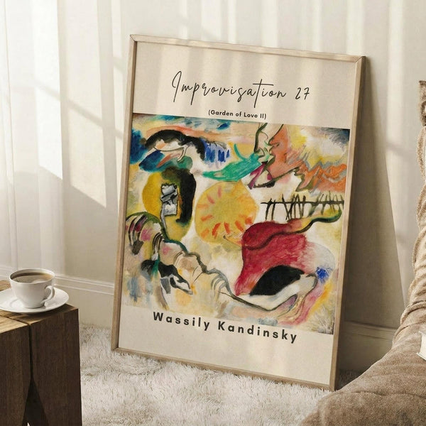 May include: A framed art print leaning against white walls on a textured white rug. The abstract painting features vibrant swirling forms in yellows, greens, blues, and reds with flowing organic shapes. A coffee cup sits on a wooden block nearby, with soft natural lighting creating shadows across the minimal room setting.