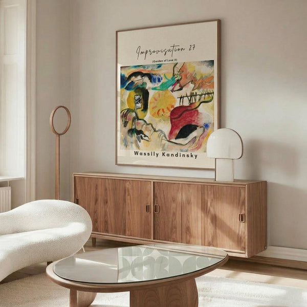 May include: Abstract colorful art print displayed above wooden sideboard in modern living room setting. Vibrant painting features bold brushstrokes in yellow, red, blue, and green with organic flowing forms. Print shown in thin wooden frame on neutral wall. Room includes curved white textured chair, glass oval coffee table, brass floor lamp, and white table lamp on sideboard.