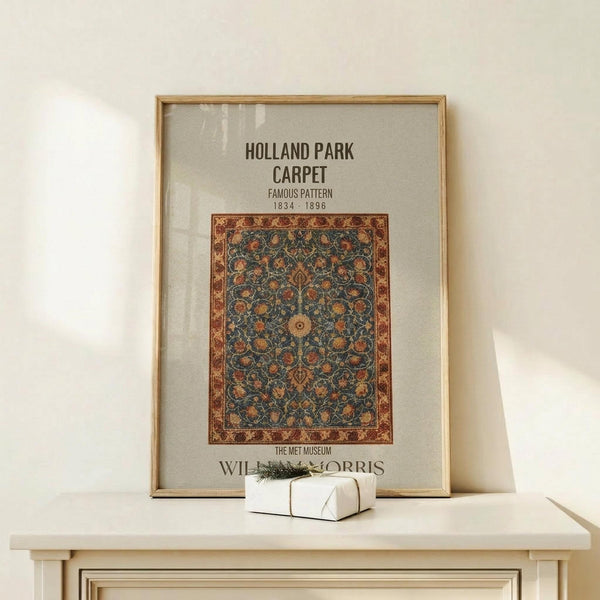 May include: Framed vintage-style poster featuring an ornate Persian-style carpet design with intricate floral patterns in blue, orange, and burgundy colors. The artwork shows museum-style text and attribution. Displayed on a light wood console table against a cream wall, with a small wrapped gift box with evergreen sprig placed in front of the frame.