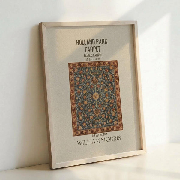 May include: Framed poster print leaning against white wall showing ornate carpet design with intricate floral patterns in blues, oranges and browns. Features decorative border and text reading "Holland Park Carpet Famous Pattern 1834-1896" and "William Morris The Met Museum" on cream background in light wood frame.