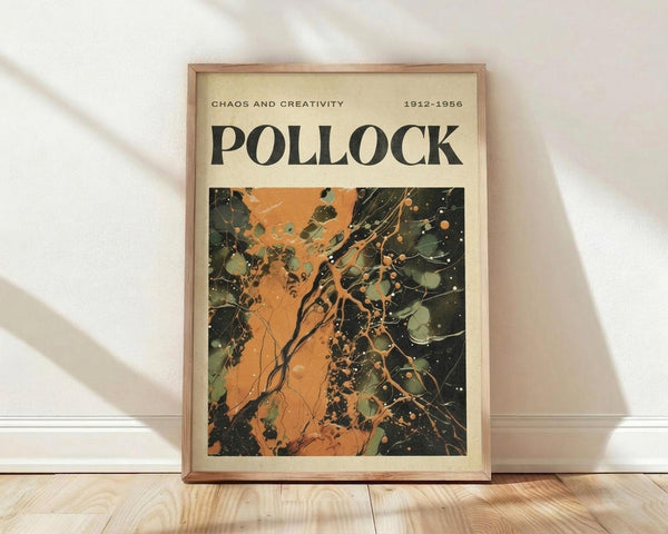 May include: Framed poster leaning against white wall on light wood floor. Poster features abstract expressionist artwork with chaotic paint splatters and drips in orange, black, green, and cream colors. Text reads "POLLOCK" in large black letters with "CHAOS AND CREATIVITY 1912-1956" above. Natural wood frame with cream matting. Soft natural lighting creates gentle shadows on textured white fabric backdrop.
