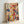 May include: Abstract expressionist artwork in light wooden frame leaning against white wall. Energetic composition features vibrant paint splatters, drips, and gestural marks in red, blue, yellow, turquoise, and black across cream background. Dynamic intersecting lines and organic paint drops create rhythmic movement throughout the piece, characteristic of action painting technique.