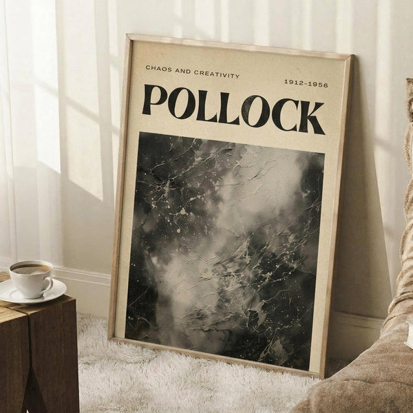 May include: Framed Jackson Pollock exhibition poster leaning against white wall beside coffee cup on wooden block and beige throw blanket. Poster features abstract black and white drip painting with "CHAOS AND CREATIVITY" and "POLLOCK 1912-1956" text on cream background in light wood frame.
