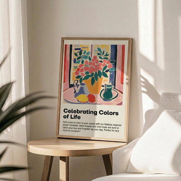 May include: Colorful Matisse-inspired still life poster in wooden frame on round wood table next to beige chair and plant. Artwork shows orange vase with red flowers, green leaves, blue pitcher, and yellow-red fruits on pink surface with striped background in vibrant fauve style colors.