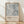 May include: Framed poster featuring abstract expressionist artwork in muted gray and white tones with dynamic brushstrokes and splatters. Text below reads "Jackson Pollock" with exhibition details "January 10-20, 1956, 8th Avenue, New York City" and "A Journey Through Chaos." Natural wood frame sits against white textured wall on light wooden floor with soft shadows from window light.