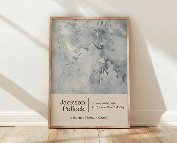 May include: Framed poster featuring abstract expressionist artwork in muted gray and white tones with dynamic brushstrokes and splatters. Text below reads "Jackson Pollock" with exhibition details "January 10-20, 1956, 8th Avenue, New York City" and "A Journey Through Chaos." Natural wood frame sits against white textured wall on light wooden floor with soft shadows from window light.