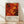 May include: Framed abstract art poster featuring vibrant red, orange, and yellow swirls with black paint splatters and circular elements in Jackson Pollock's signature drip painting style. The artwork is displayed in a light wood frame against a white wall with natural lighting creating soft shadows. Exhibition text below reads "Jackson Pollock January 10-20, 1956 8th Avenue, New York City A Journey Through Chaos" on cream background.