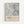 May include: Framed poster print hanging on white wall featuring abstract expressionist artwork in muted grays and blues with scratched, dripped paint textures. Lower portion displays cream-colored text area with artist name, exhibition dates, and location details. Natural wood frame surrounds the vertical rectangular print.