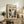 May include: Framed vintage-style art poster featuring abstract black and white Jackson Pollock painting with chaotic drip patterns and organic forms, displayed on rustic wooden sideboard alongside fern plant, ceramic vase, and books in warm neutral living room setting with beige armchair