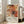 May include: Abstract expressionist artwork poster with vibrant orange, red, and black paint splatters and white geometric line overlays, displayed in light wooden frame leaning against white wall next to beige upholstered sofa in bright, naturally lit room with hardwood floors and large windows.