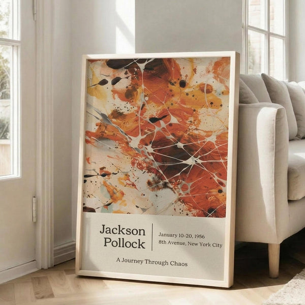 May include: Abstract expressionist artwork poster with vibrant orange, red, and black paint splatters and white geometric line overlays, displayed in light wooden frame leaning against white wall next to beige upholstered sofa in bright, naturally lit room with hardwood floors and large windows.